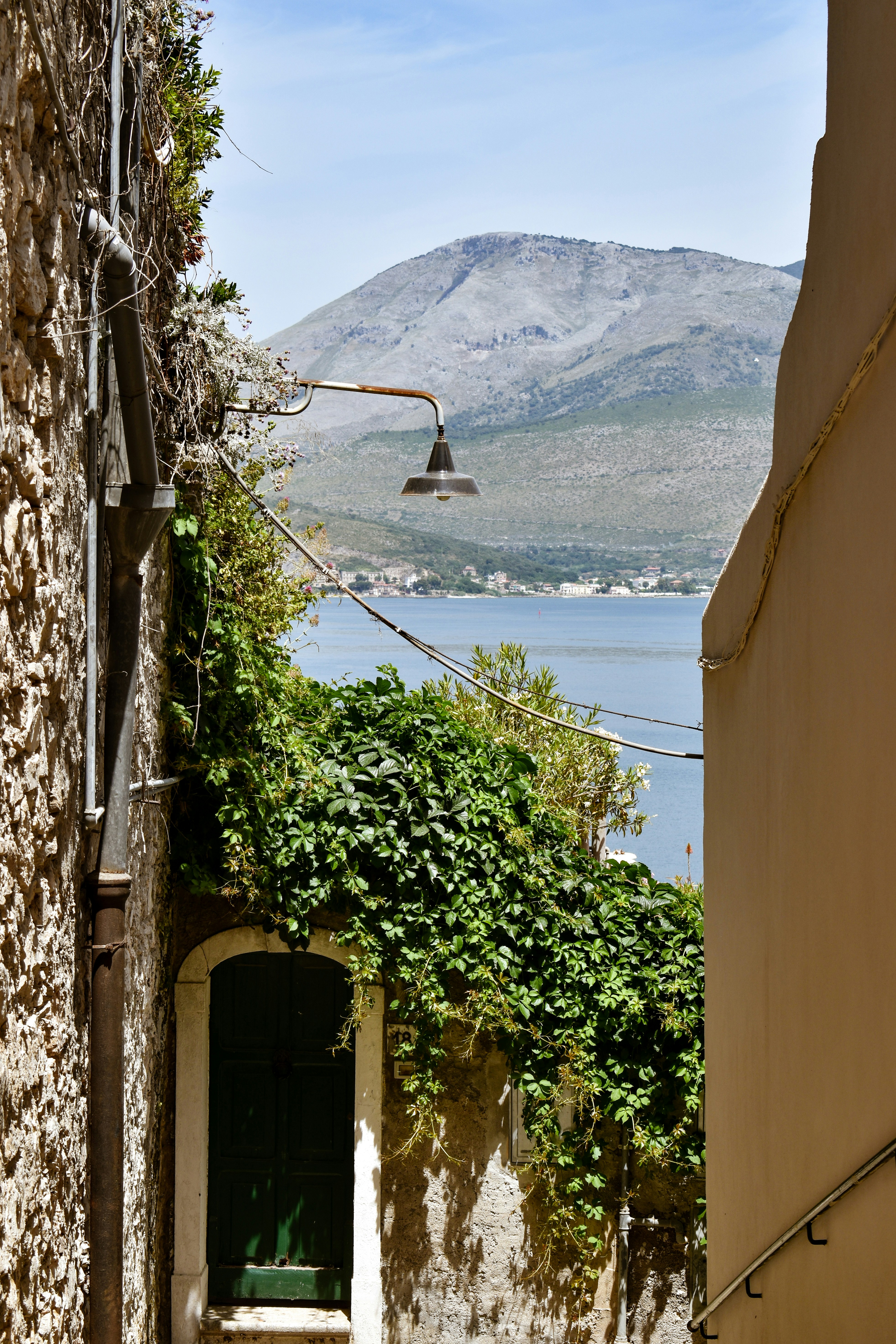a stone building with a bell on top and a body of water in the background