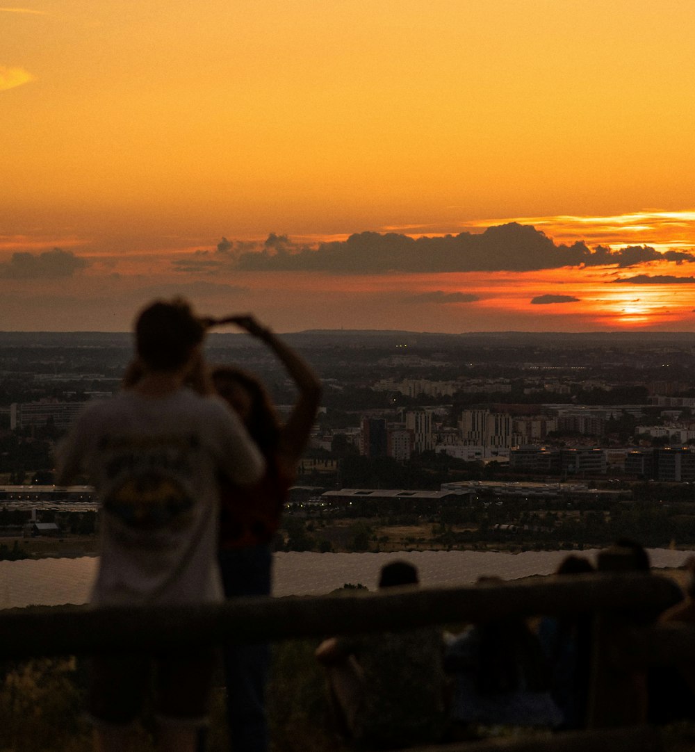 a person standing on a balcony overlooking a city at sunset