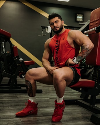 Man wearing modern, fitted workout clothes with red accents in a gym setting.