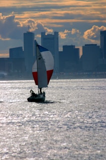 Wide view of the sailboat cutting through sparkling water with Lisbon's sun-kissed skyline in the background.