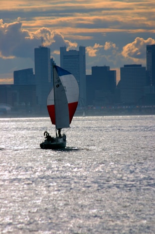 Wide view of the sailboat cutting through sparkling water with Lisbon's sun-kissed skyline in the background.