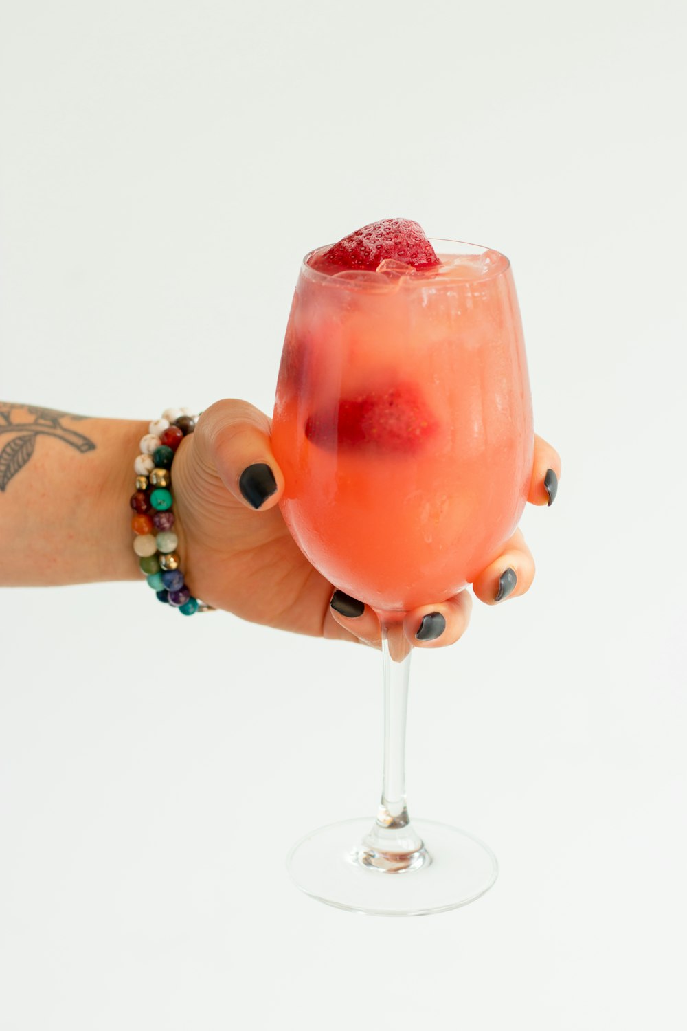 a hand holding a glass of red liquid