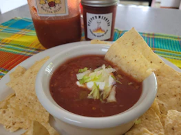 Close-up of a vibrant salsa bowl surrounded by fresh vegetables and handmade tortillas.