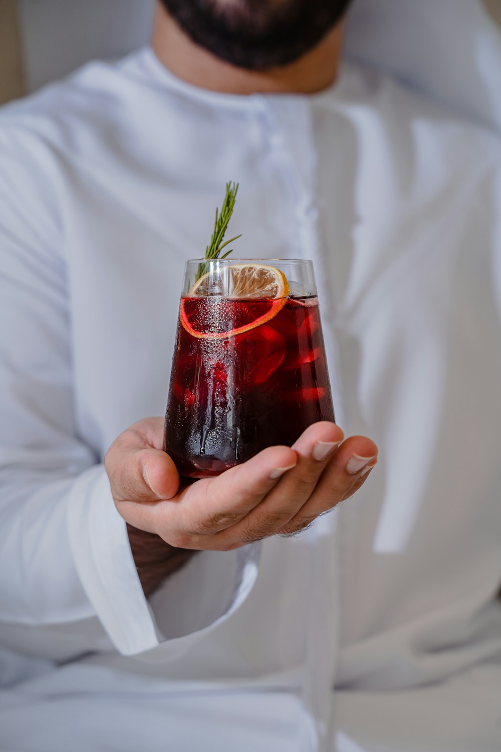 a man holding a glass of red liquid