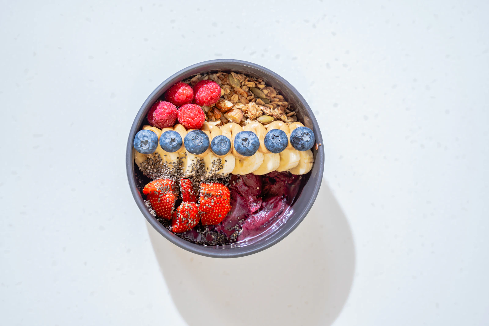 Bol garni de granola, oléagineux, graines et fruits frais