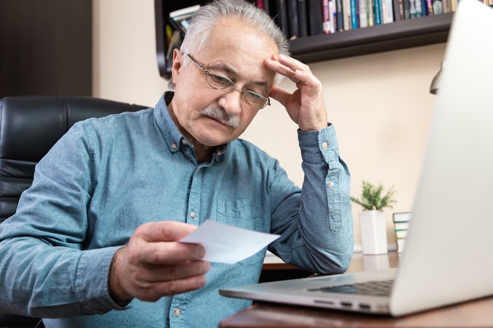 a man holding a pen and looking at a laptop