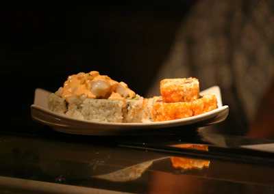 Close-up of vibrant classic sushi rolls glowing under neon lights on a black plate.