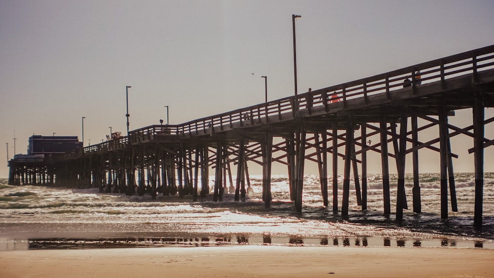 a pier with a beach and a building in the background