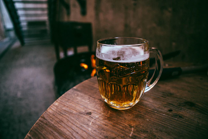 Tall pilsner glass full of pale-gold lager on a wooden table