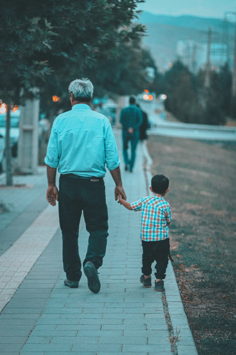 a person and a child walking on a sidewalk