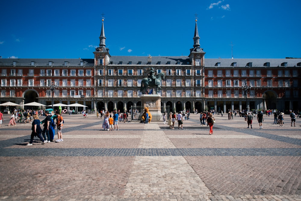 a large building with a statue in front of it with Plaza Mayor, Madrid in the background