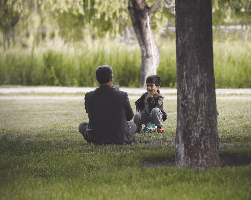 a man and a child sitting under a tree