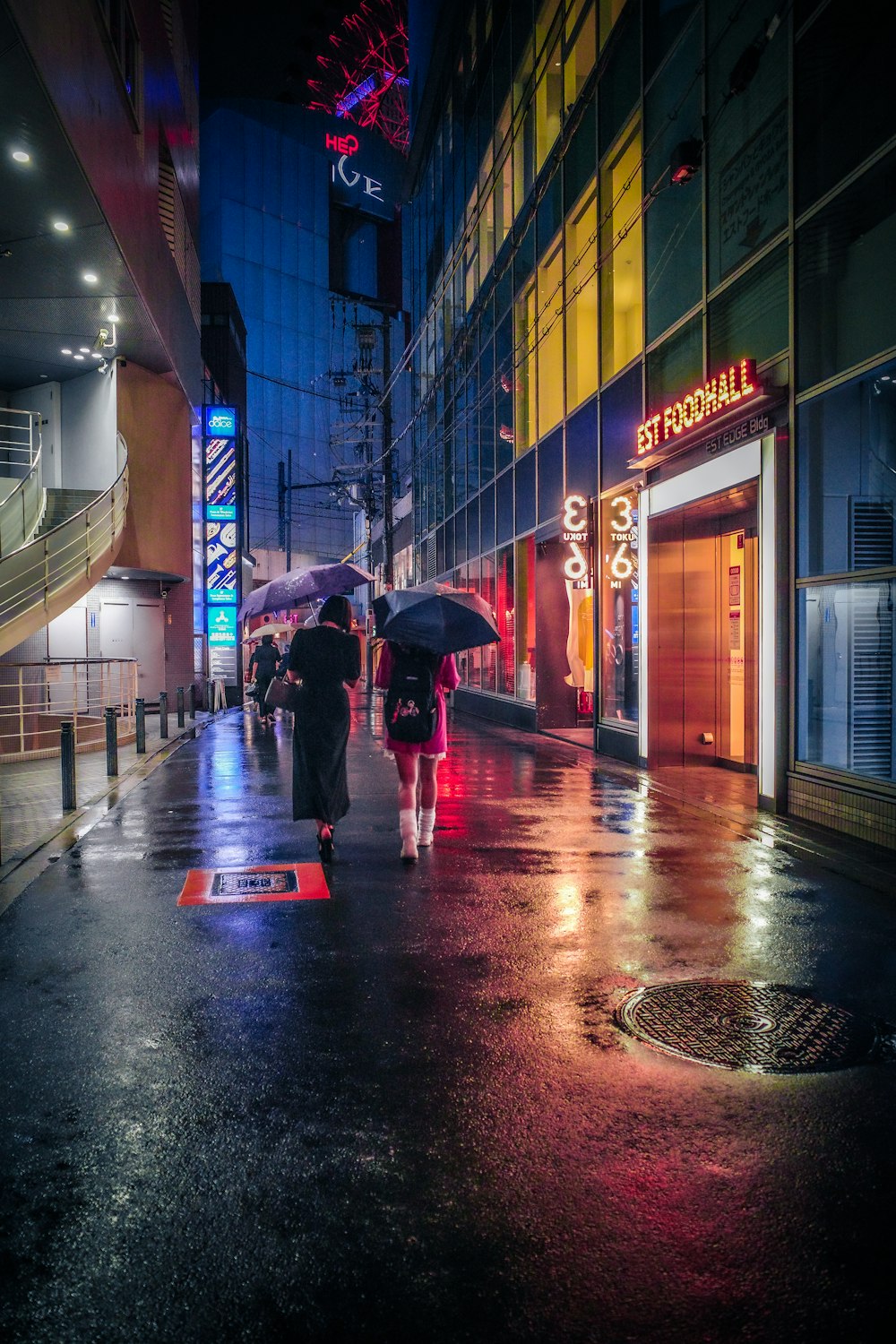 people walking down a sidewalk with umbrellas