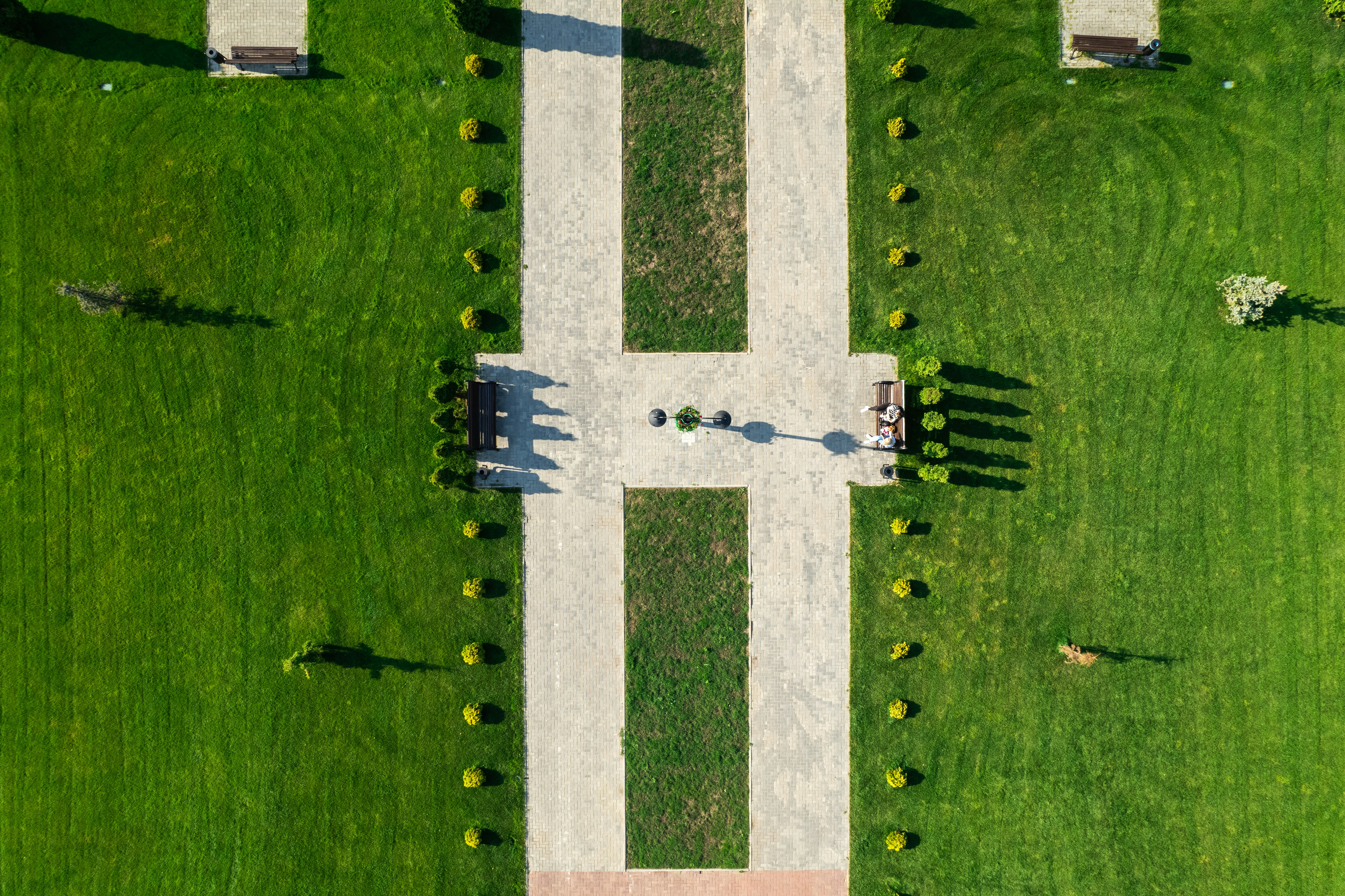 a large green field with a white stone pillar and a cross