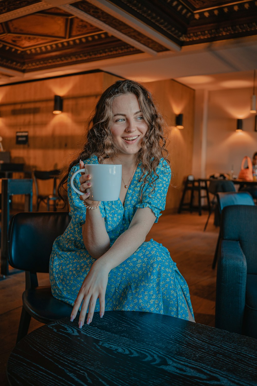 a person sitting at a table holding a cup