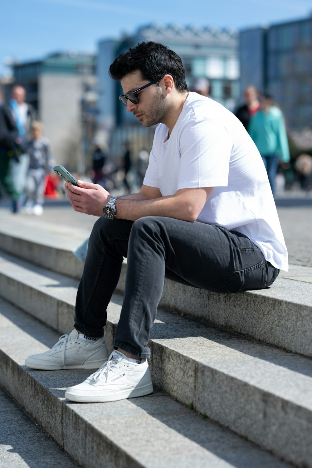 a man sitting on a ledge looking at his phone