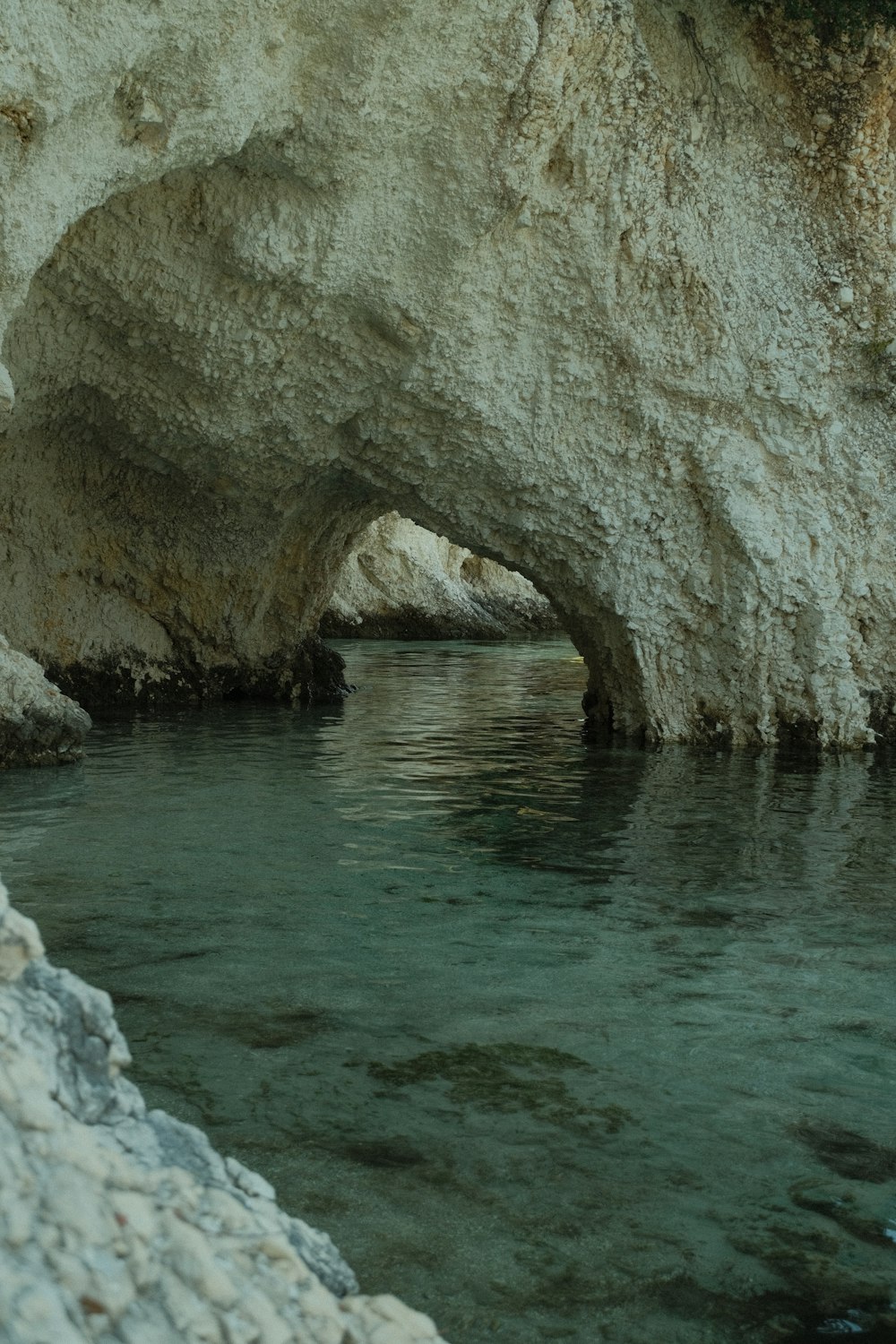 a body of water with a rock arch over it