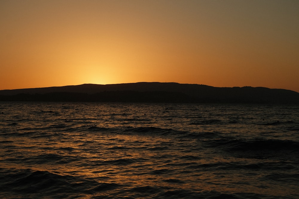 a body of water with a hill in the background