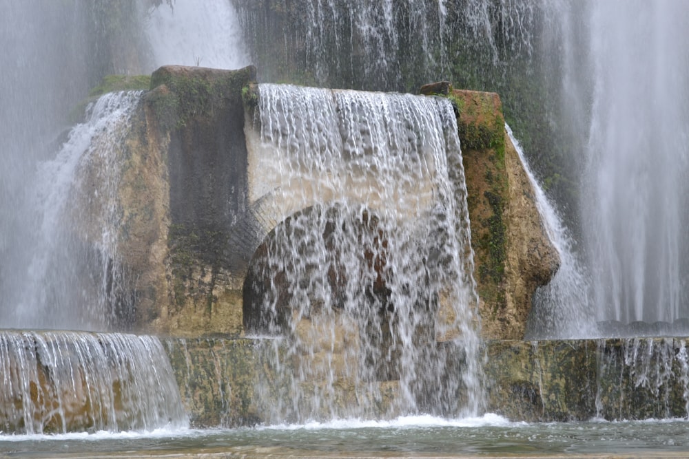 a waterfall with a rock wall