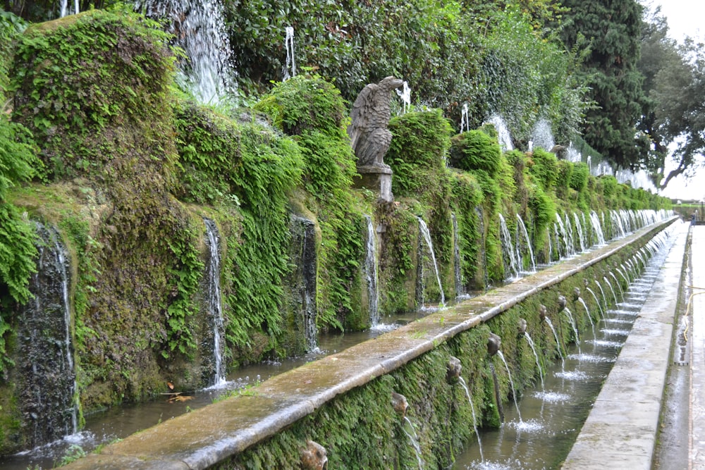 a bridge with a waterfall and a statue on it