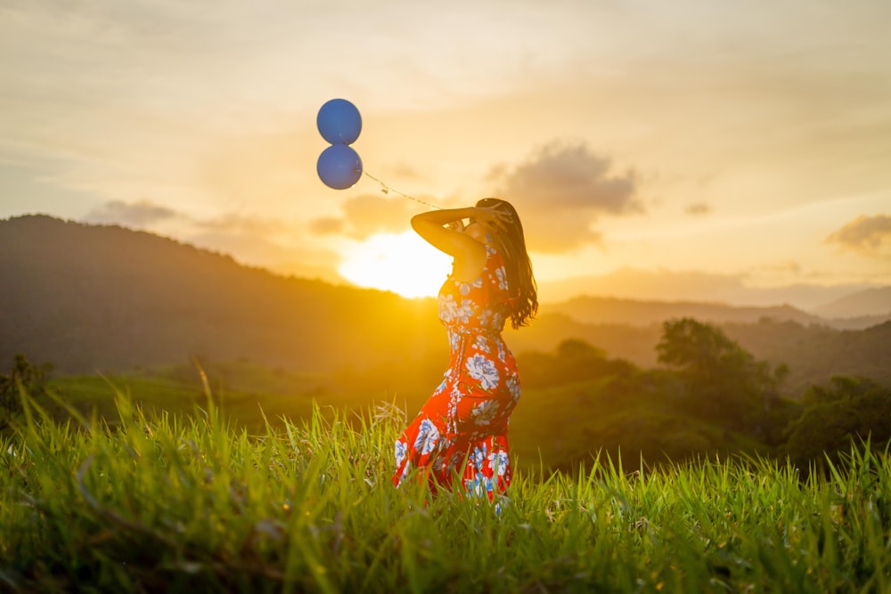 a person holding balloons in a field