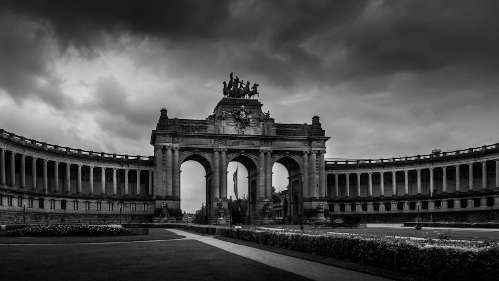 a large building with a clock tower with Cinquantenaire in the background