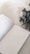 An open monthly planner lies on a smooth, neutral-colored surface. The pages contain sections for key reminders, goals, and tasks to complete. A branch of eucalyptus leaves is placed beside the planner, adding a touch of greenery and natural texture.