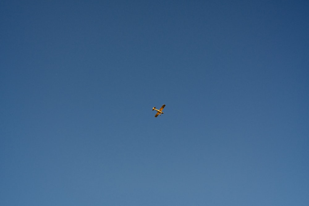 a yellow plane flying in the sky