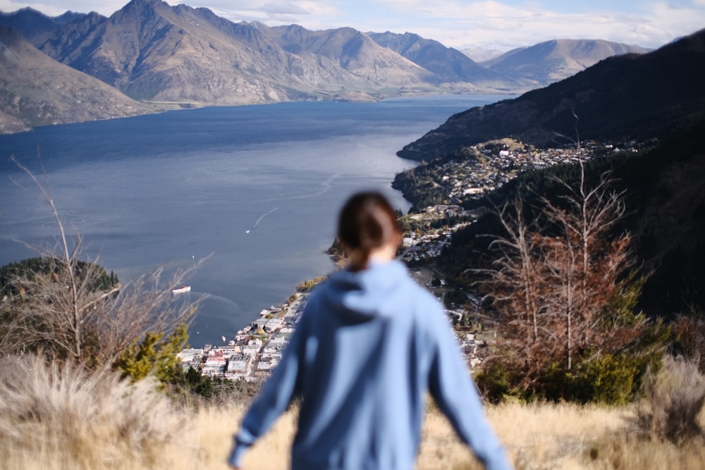 a person standing on a hill overlooking a lake and mountains