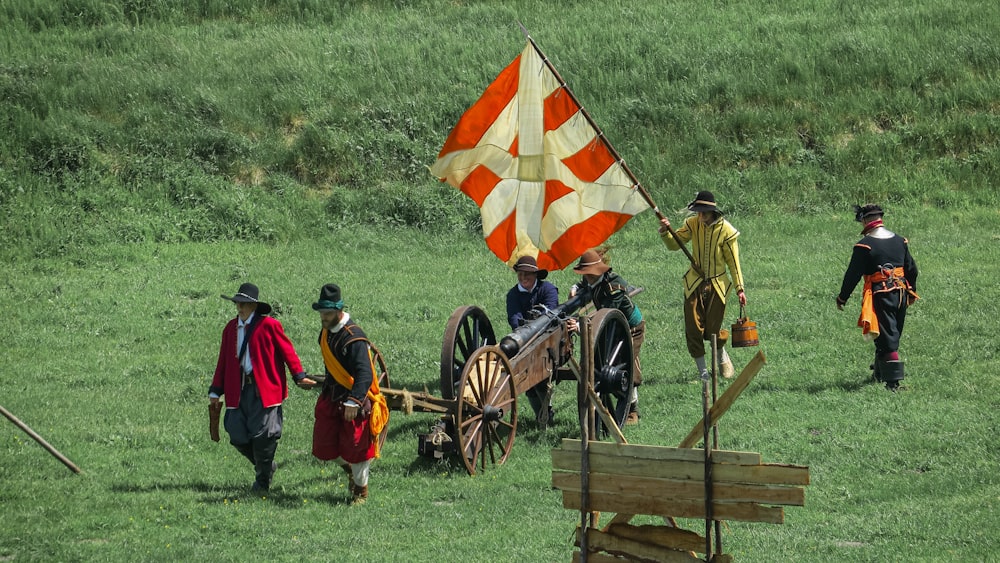 a group of people in clothing with a flag and a cart with a flag