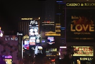 A cityscape at night illuminated by digital billboards showcasing casino ads.