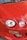 The close-up image features the front part of a red car with distinct circular headlights and smooth body contours. Reflections of trees are visible on the shiny surface of the car's hood, indicating that the car is outdoors.