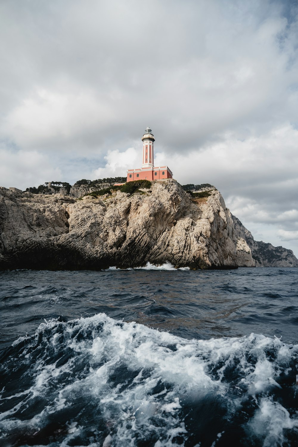 a lighthouse on a rocky cliff with Cape Neddick Light in the background