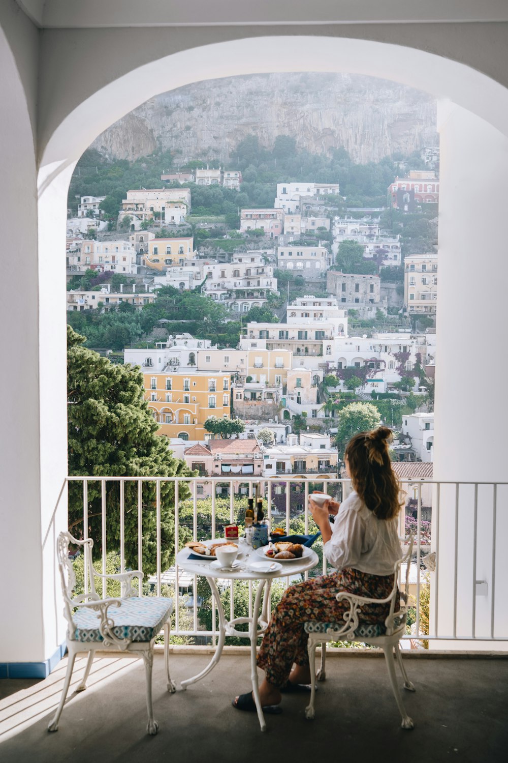 a couple of women sitting at a table looking out a window at a city