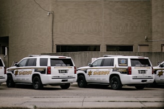 a couple of white cars parked in front of a building