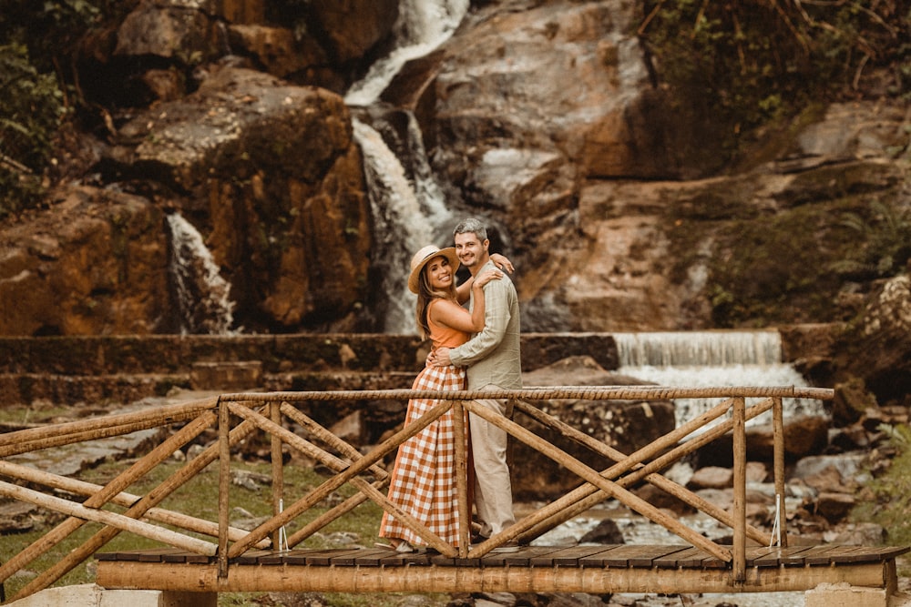 a man and woman posing for a picture in front of a waterfall