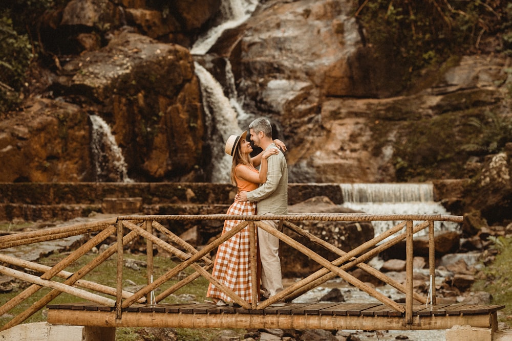 a couple kissing in front of a waterfall