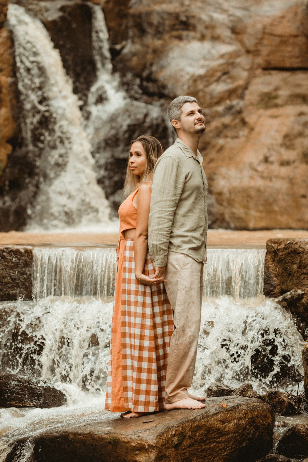 a man and woman standing in front of a waterfall