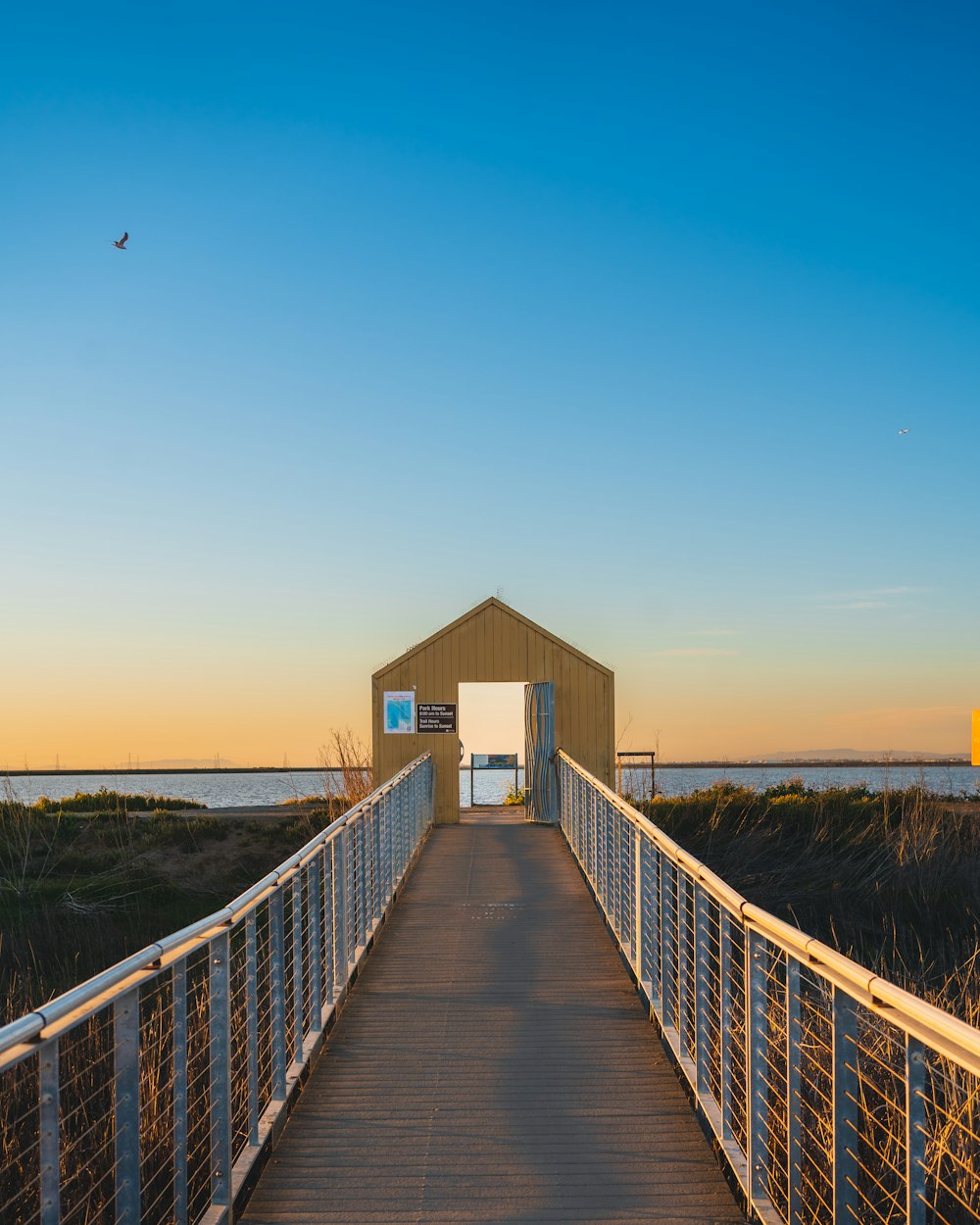 a wooden walkway with a small building on the end