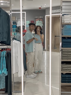 A smiling couple arranging clothes on hangers in their new store.