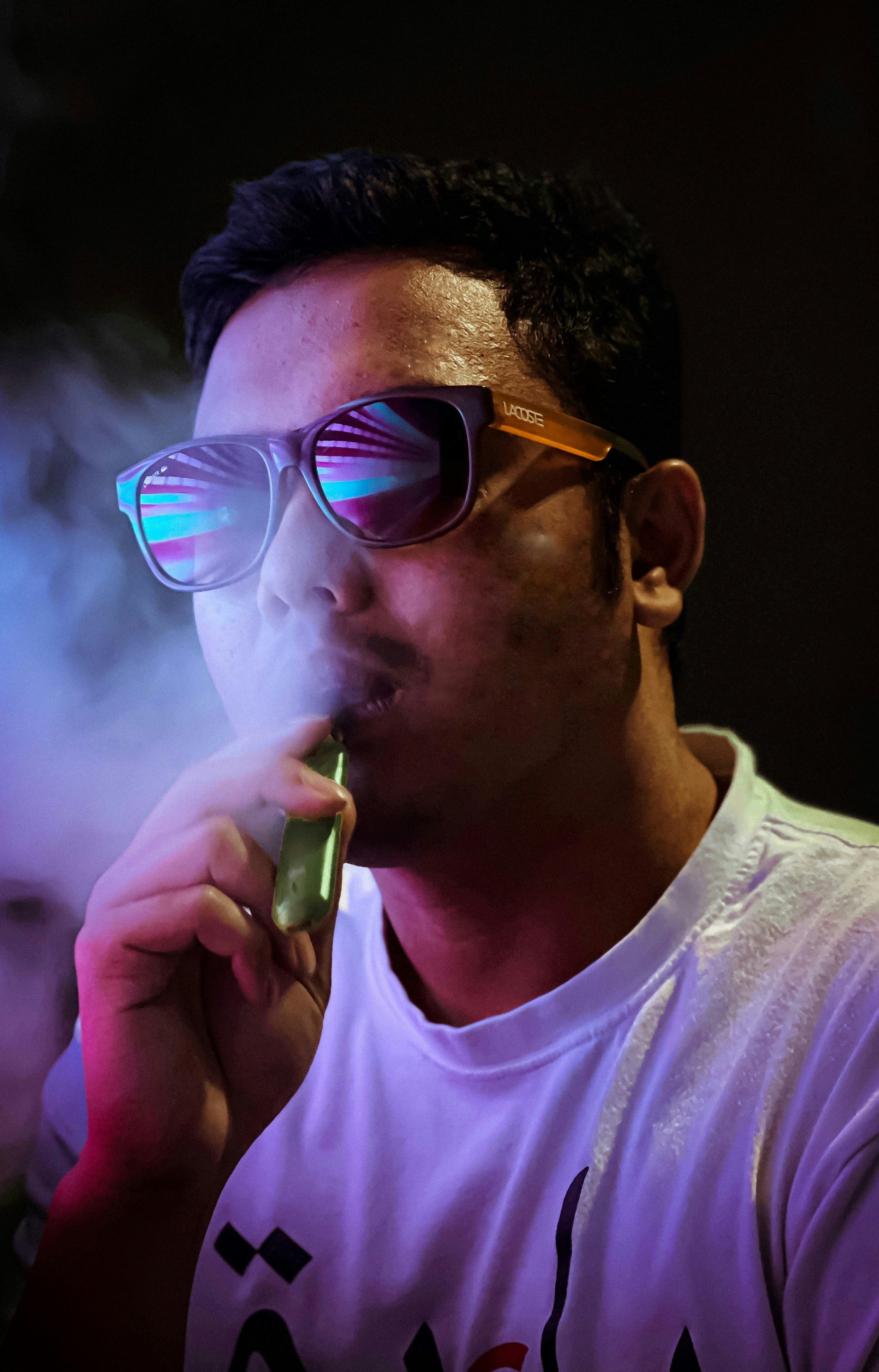 a man wearing sunglasses and eating a green object