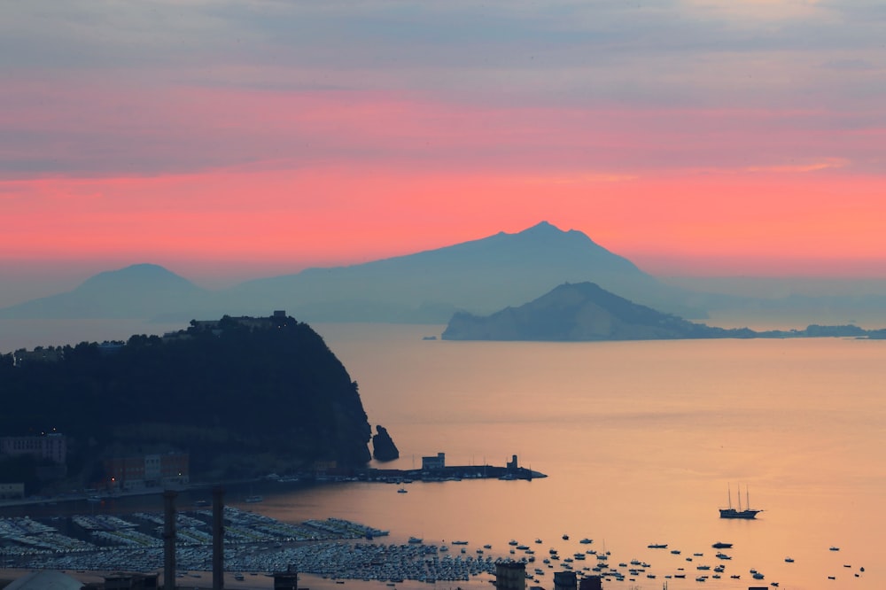 a body of water with boats in it and mountains in the background