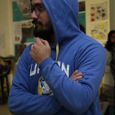 a man wearing a blue hoodie and holding a yellow stick