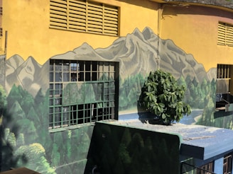 Artists and community members painting a vibrant mural featuring mountains and coastal scenes.