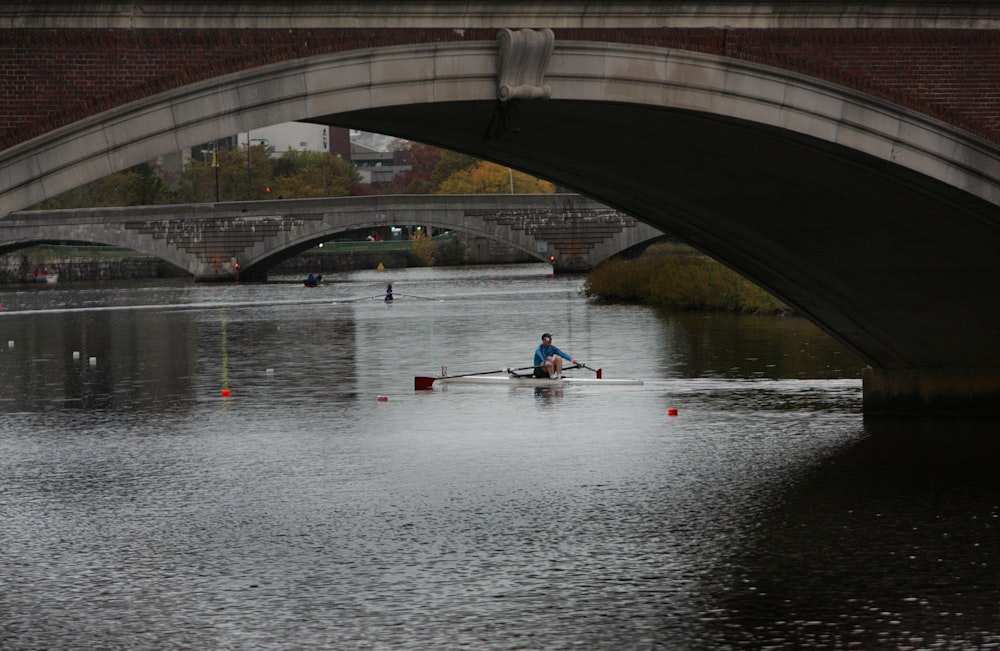 a person rowing a boat under a bridge