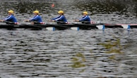 A team of rowers synchronizing their strokes on the calm waters of a Cali river.