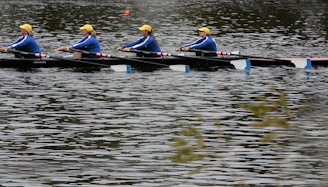 A team of rowers synchronizing their strokes on the calm waters of a Cali river.