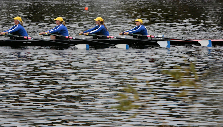 A dynamic dragon boat team rowing in perfect sync across shimmering water under a clear blue sky.
