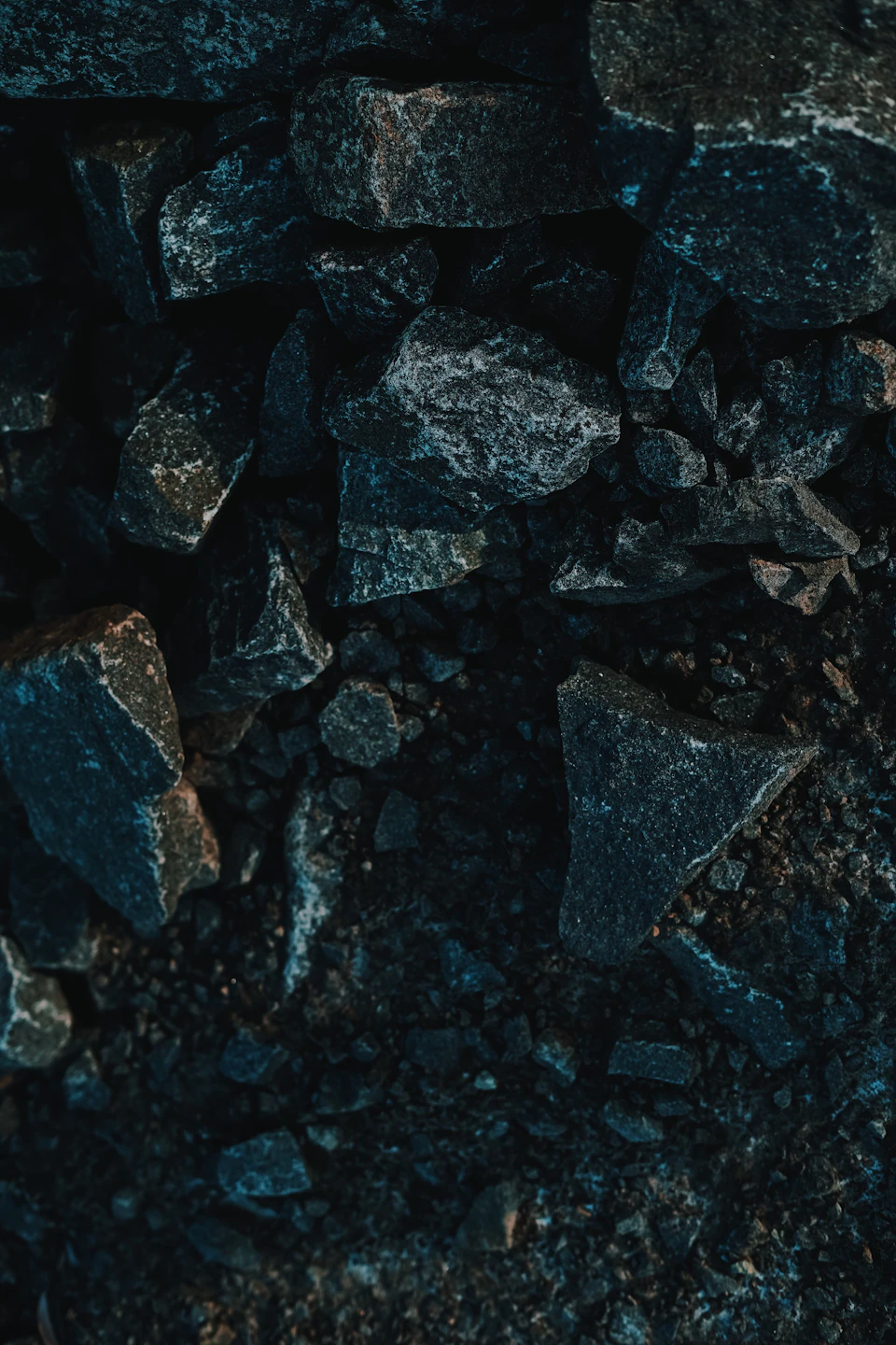Close-up view of scattered black rocks on a dark surface, varying in size and shape