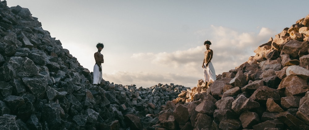 a couple of men standing on a rocky hill